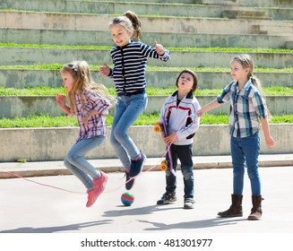 Young girl jumping while jump rope game with friends outdoor