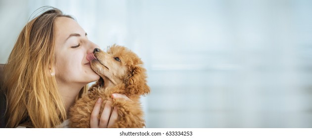 Young girl kissing her good friend dog . Background.