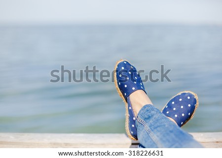 Young girl laying near the sea and resting in funny sneakers