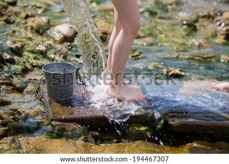 young girl legs under pure water stream