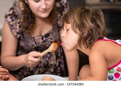 Young Girl Licking Chocolate Off A Spoon