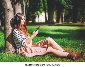 Young Girl Listening To Music In City Park