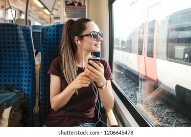 A young girl listens to a music or podcast while traveling in a train. - Powered by Shutterstock