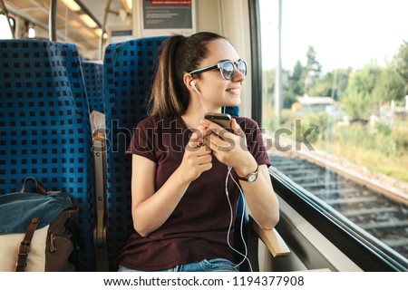 A young girl listens to a music or podcast while traveling in a train.
