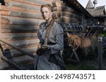 a young girl with a long blond braid in a folk costume, in a village among wooden architecture, Slavic or Nordic style