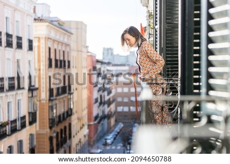 Young girl is looking the city at the balcony, looking down