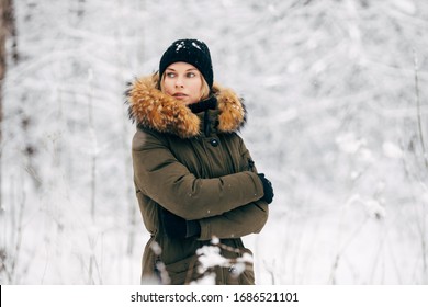 Young girl looking at side on background of snowy trees on walk in winter forest