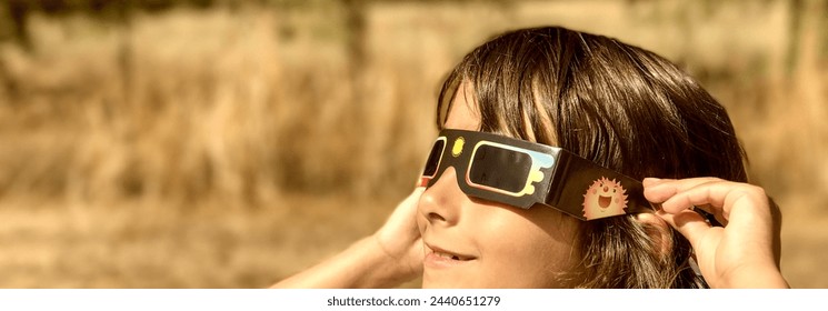 A young girl looking at the sun during a solar eclipse on a country park, family outdoor activity.