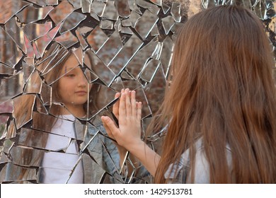 Young Girl Looks In A Broken Mirror And Shows Her Hand On A Mirror