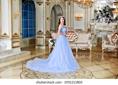 A young girl looks like a princess in a blue long dress. The image of Cinderella wearing a crown. The image of a young girl at the prom.
