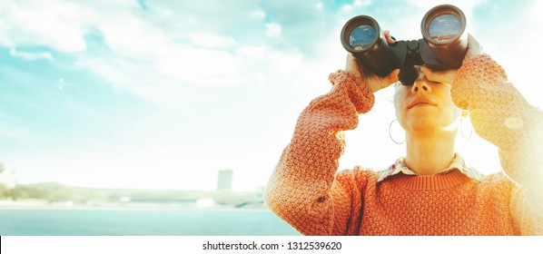 Young Girl Looks Through Binoculars At The Sea On A Bright Sunny Day. Travel Concept