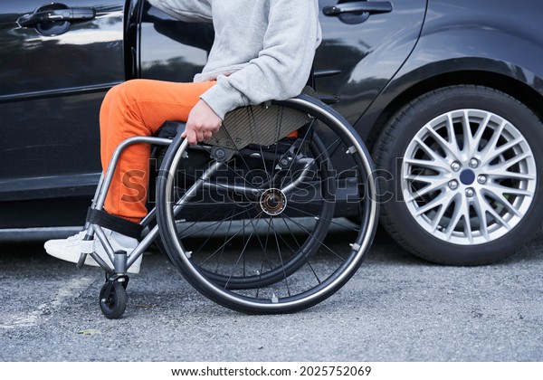 Young girl with lower body\
disability switches position from the wheelchair into the\
car