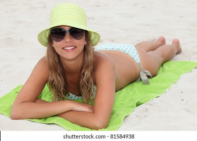 Young Girl Lying On A Lime Green Towel On The Beach