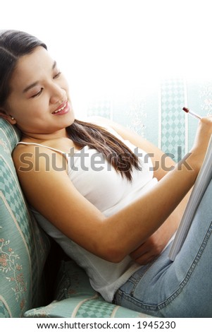 A young girl lying on a sofa thinking and writing