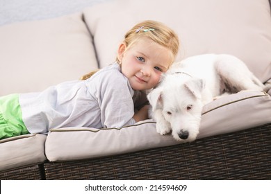 Young Girl Lying With Pet Dog On Couch