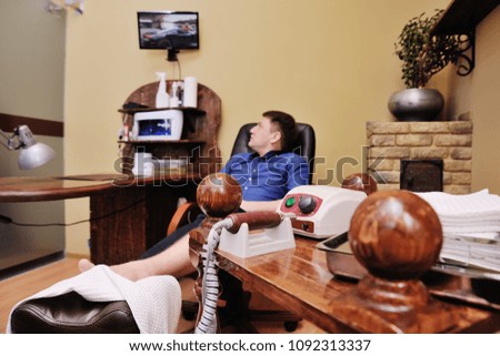 a young girl makes a man pedicure in the background of a beauty salon. Nail care