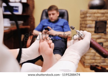 a young girl makes a man pedicure in the background of a beauty salon. Nail care