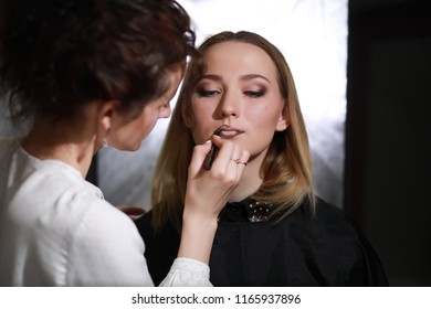 Young girl with a make-up artist in the studio in front of a mirror - Shutterstock ID 1165937896