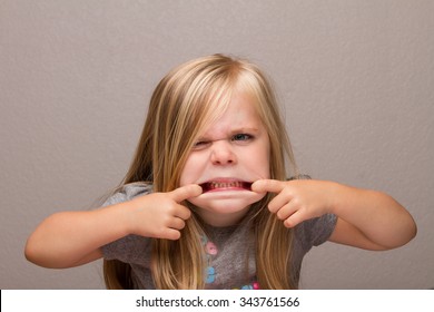 Young Girl Making Funny Faces Showing Her Teeth