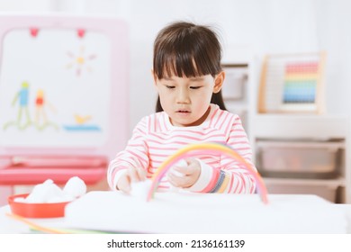 Young Girl Making Rainbow Craft Using Pipe Cleaner At Home