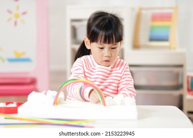 Young Girl Making Rainbow Craft Using Pipe Cleaner At Home