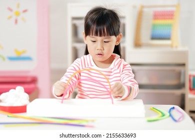 Young Girl Making Rainbow Craft Using Pipe Cleaner At Home