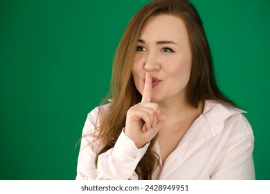 Young girl making silence gesture on green background. High quality photo