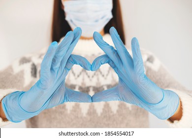 Young girl in a medical mask showing the symbol of a heart gloved hands - Shutterstock ID 1854554017