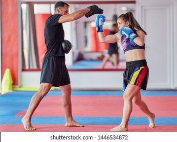 Young Girl Muay Thai Fighter And Her Coach Hitting Mitts In The Ring