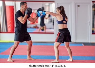 Young Girl Muay Thai Fighter And Her Coach Hitting Mitts In The Ring