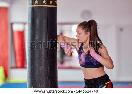 Young girl muay thai fighter working with the heavy bag