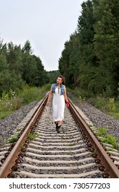 young girl in old-fashioned clothes walking on rails