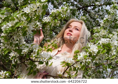 Young girl on the background of blossoming apple trees in the garden