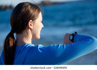 Young Girl On Beach Checking Heart Rate After Run