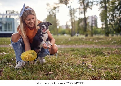 A Young Girl On A Beautiful Day In The Park Is Having A Good Time While Cleaning Up After Her Dog. Friendship, Walk, Pets