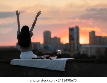 young girl on a city rooftop having a picnic and watching gorgeous sunset - Powered by Shutterstock