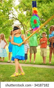 Young girl at an outdoor party hitting a pinata