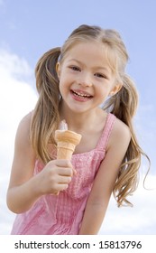 Young Girl Outdoors Eating Ice Cream Cone And Smiling