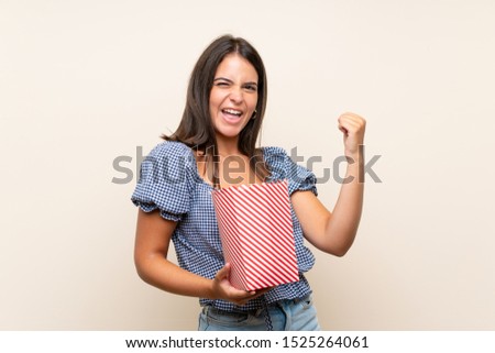 Young girl over isolated background holding a bowl of popcorns