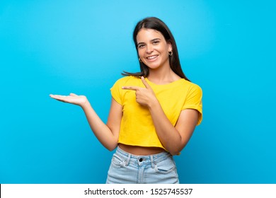 Young girl over isolated blue background holding copyspace imaginary on the palm to insert an ad - Shutterstock ID 1525745537