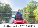 young girl paddles in a red paddle boat / kayak on the Zschopau dam Kriebstein in Saxony