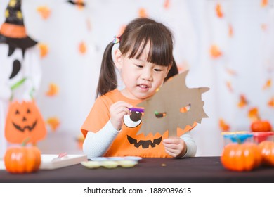 Young Girl Painting Witch Mask For Halloween Party At Home 