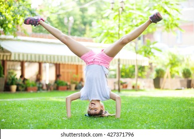 Young Girl Performing Headstand In Park