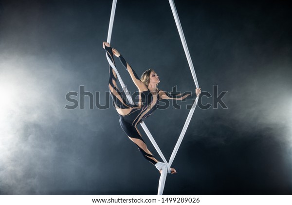 A\
young girl performs the acrobatic elements in the airrial silk.\
Studio shooting performances on a black\
background