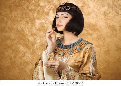 Young Girl With Perfume Bottle. Glamorous Closeup Portrait Of Beautiful Sexy Stylish Brunette Young Woman Model With Bright Makeup With Gold Jewelery. Cleopatra