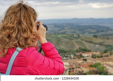 Young girl photographer takes pictures of the hills of Tuscany