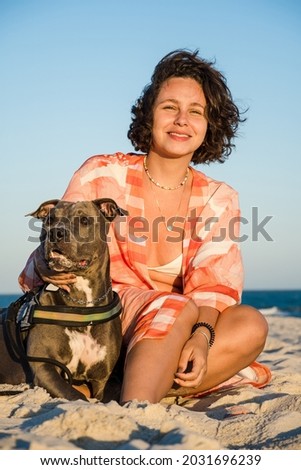 Young girl and pit bull dog in a moment of affection on the beach of Saquarema in Rio de Janeiro. Sunset.