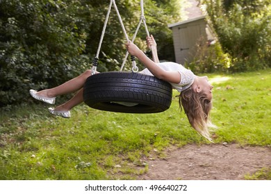 Young Girl Playing On Tire Swing In Garden