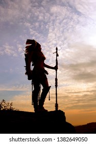 A Young Girl Plays The Part Of A Native American Indian. She
Dresses Up Wearing A Feathered Headdress And Poses
Outdoors With The Sun Setting In The Distance.