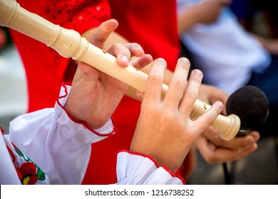 A young girl plays a wooden flute. Performing a musical composition on a flute